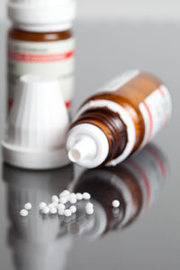Bottle of homeopathic pills spilling out onto a table