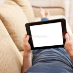 Man relaxing with tablet pc, laying on sofa