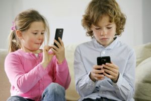 due bambini sul divano con smartphone